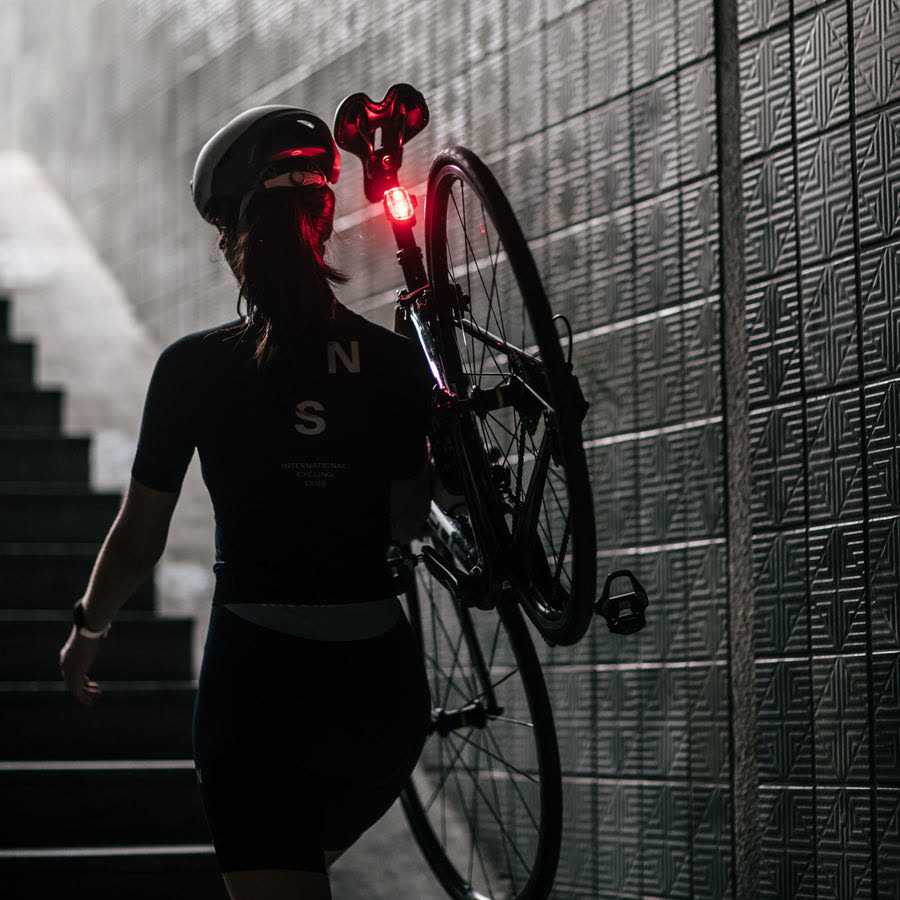 Rider carrying bike down stairs, Cliq glowing